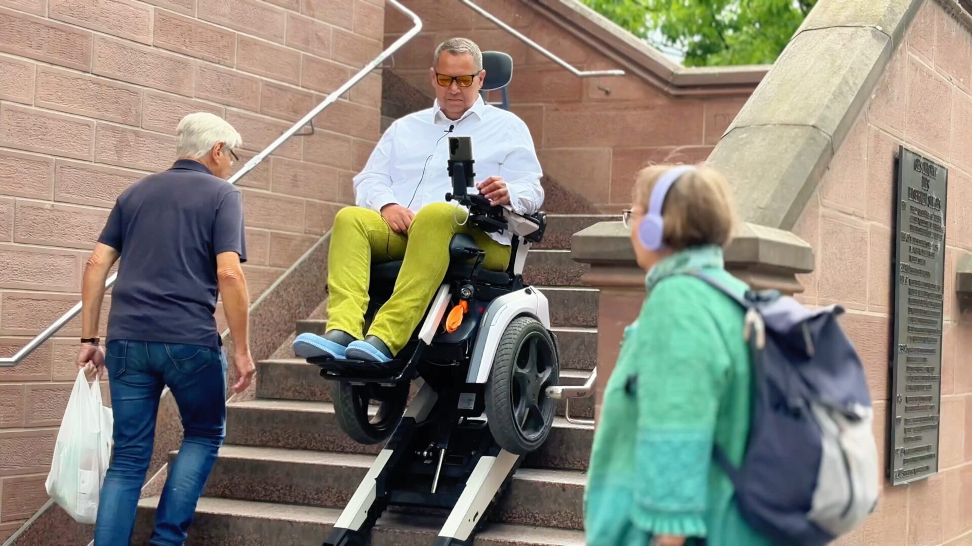 Daniel Fuks fährt in seinem treppensteigenden Elektrorollstuhl Scewo BRO auf dem eisernen Steg in Frankfurt die Treppen herunter