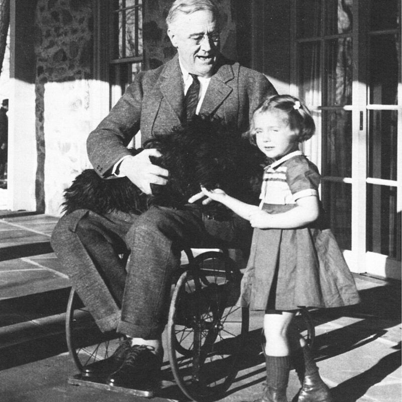 Us President Franklin D. Roosevelt in his wheelchair and a dog on his lap and a little girl standing in front of him