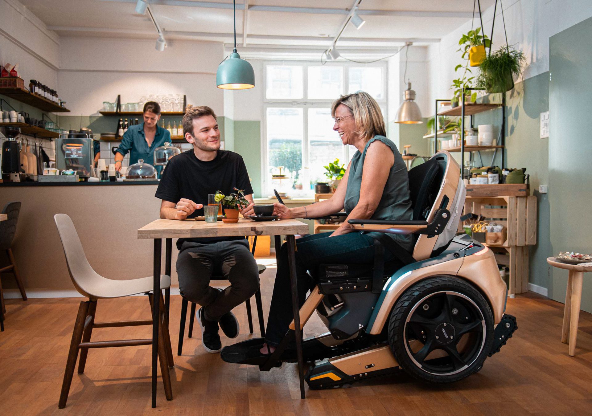 Frau im Scewo BRO unterhält sich mit einem Mann an einem Cafétisch.