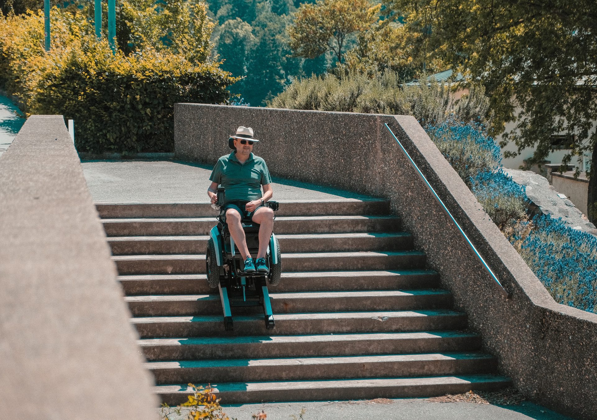 Mann fährt im Scewo BRO eine Steintreppe hinunter, umgeben von blauen Blumen.