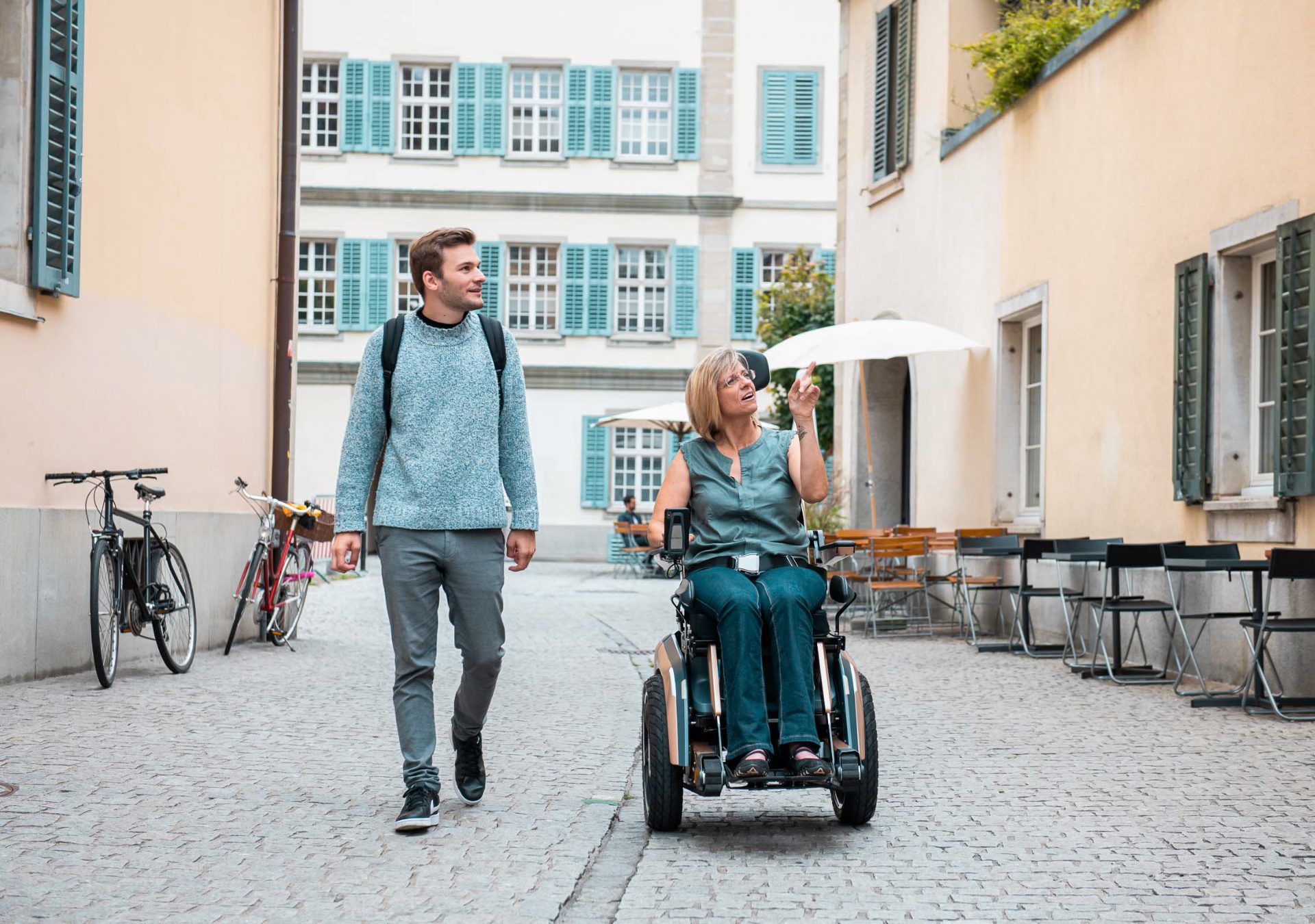 Frau im Scewo BRO unterhält sich mit einem Mann in einer Altstadtgasse.